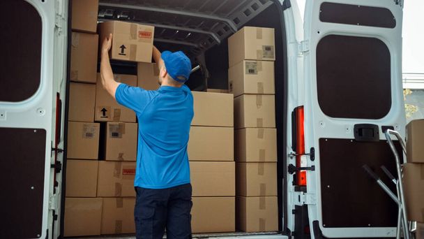 Courier Takes out Cardboard Box Package from Delivery Van Full of Parcels, Delivering Postal Parcel. - Fotoğraf, Görsel