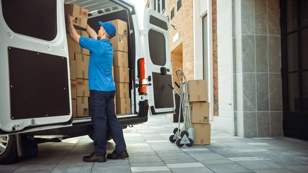 Delivery Man Uses Hand Truck Trolley Full of Cardboard Boxes and Packages, Loads Parcels into Truck Van. Professional Courier Loader helping you Move, Delivering Your Purchased Items Efficiently - Φωτογραφία, εικόνα