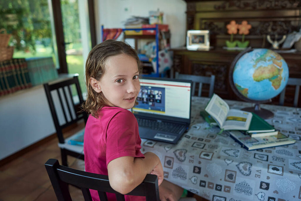 Kameraya bakan kız dizüstü bilgisayarın önünde ders çalışıyor. - Fotoğraf, Görsel