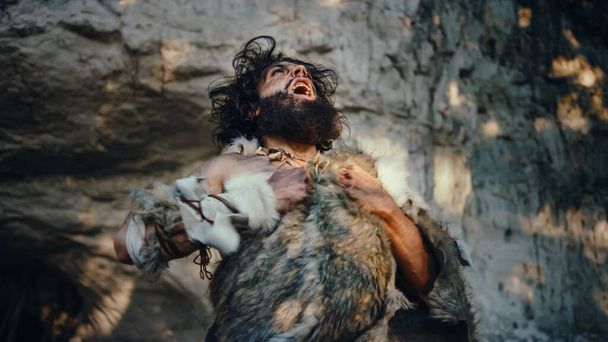 Portrait of Primeval Caveman Wearing Animal Skin Looks Around Forest Defending His Cave and Territory in the Prehistoric Times. Prehistoric Neanderthal or Homo Sapiens Leader - Zdjęcie, obraz