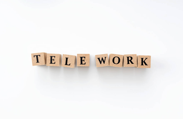 A wooden block with the word tele work written on it on a white background - Photo, image