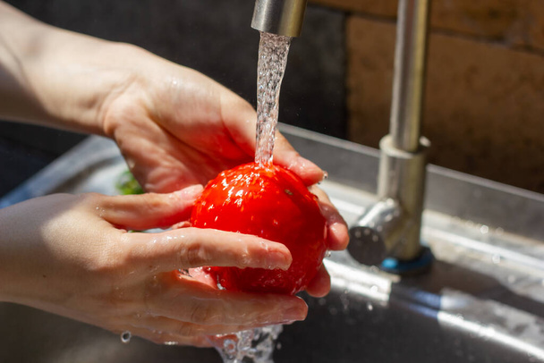 hands of woman washing a tomato in kitchen - Fotoğraf, Görsel