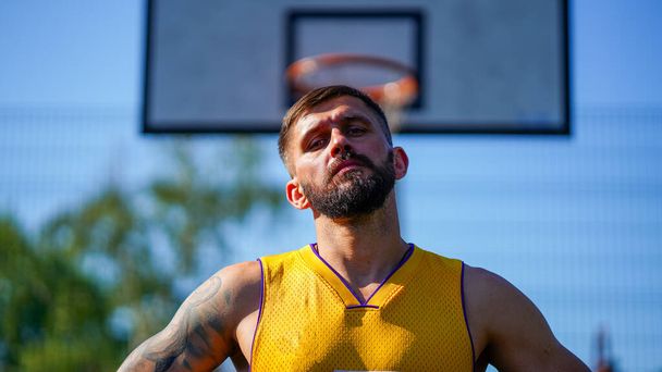 Clous-up portrait of skilled athlet with beard in yellow jersey on basketball court - Фото, зображення