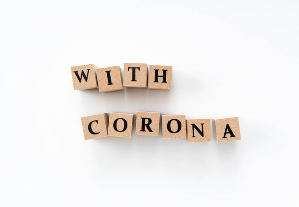 Un bloque de madera con la palabra "con corona" escrita sobre un fondo blanco
 - Foto, Imagen