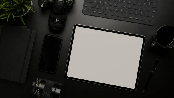 Top view of blank screen tablet on dark modern workspace with digital devices, supplies and decoration - Photo, image