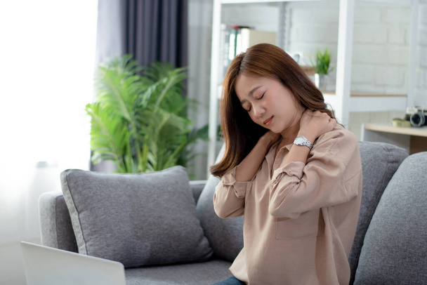 As mulheres jovens se sentem cansadas depois de usar um laptop por um longo tempo. Ela está massageando o pescoço e as costas
. - Foto, Imagem