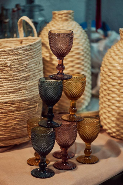 A vertical picture of vintage colorful glasses on each other against straw woven baskets - Valokuva, kuva