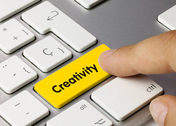 Creatividad escrita en la tecla amarilla del teclado metálico. Pulsando la tecla
. - Foto, Imagen