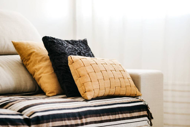 A closeup of black and yellow pillows on a white sofa - 写真・画像