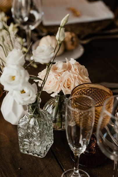 A vertical shot of wine glasses and flowers in a vase on the table - Foto, Bild
