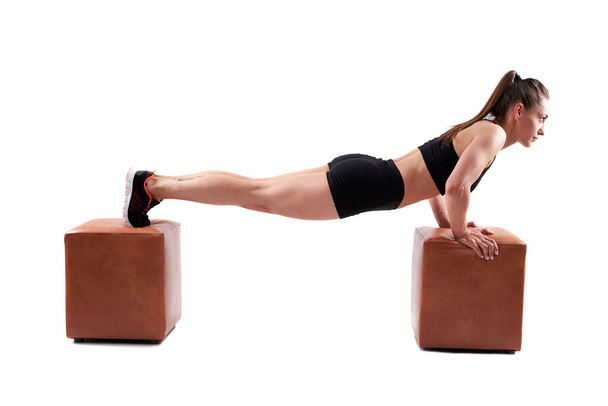 Young hispanic female fitness model doing pushups on white background - Photo, image