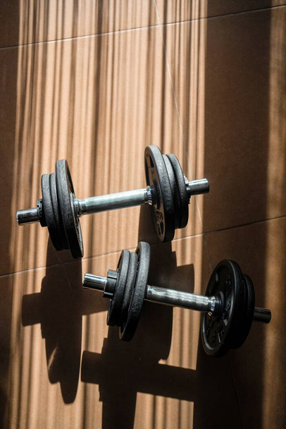 A vertical shot of two iron dumbbells on the floor - the concept of a healthy lifestyle and sport - Zdjęcie, obraz