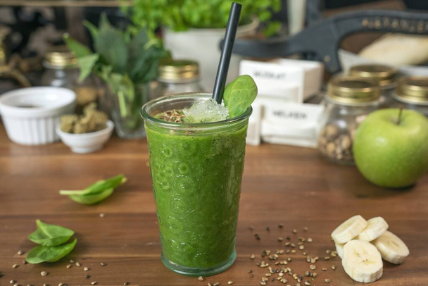 A closeup shot of a green smoothie on the table next to the apple - Fotó, kép