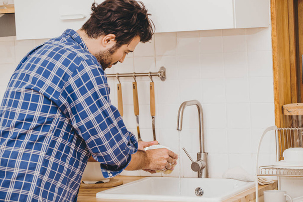 男やもめ家事や家の仕事だけで家に滞在中に台所で食器洗い機を掃除 - 写真・画像