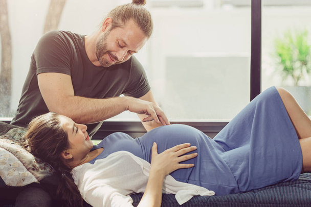 Schwangere Frau bleibt zu Hause mit netten Mann niedlich spielen mit Babybauch. - Foto, Bild