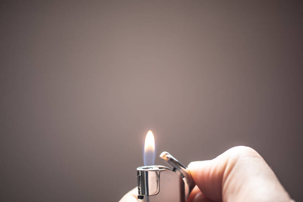 Zapalovač hoří malým plamínkem, který osvětluje okolí - Fotografie, Obrázek