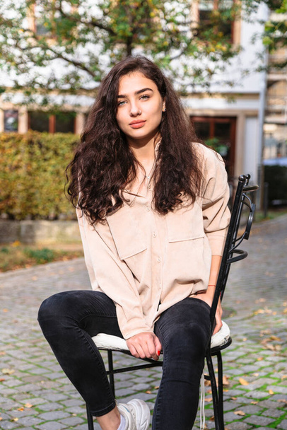 Girl sitting on chair in street on wood background - Фото, зображення