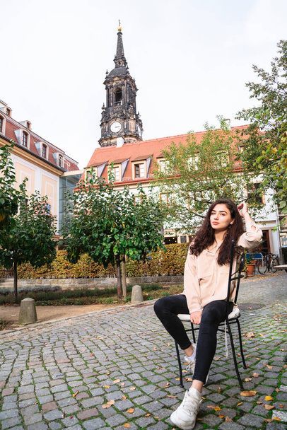 Brunette girl sitting on chair in part of old city - Foto, afbeelding
