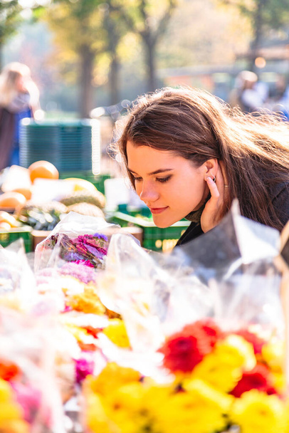 Young girl at street flower shop smells bouquet - Foto, afbeelding
