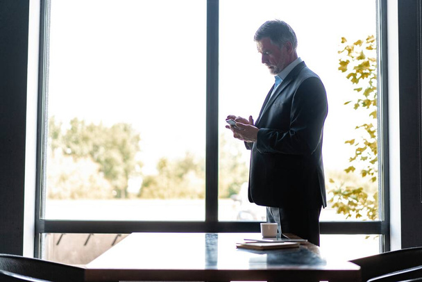 Businessman using mobile phone app texting. Mature caucasian man holding smartphone for business work - Φωτογραφία, εικόνα