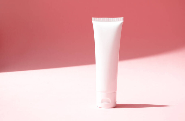 Single mockup moisturizer cream white container on cute pink background. Beauty product white plastic tube with trendy shadow and copy space, front view.  Concept delicate, lightness and pure skincare - Photo, Image