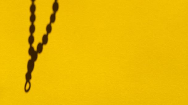 Japa Perlen Schatten auf gelbem Pastellpapier. Abstrakter Hintergrund. Archivfotografie. - Foto, Bild