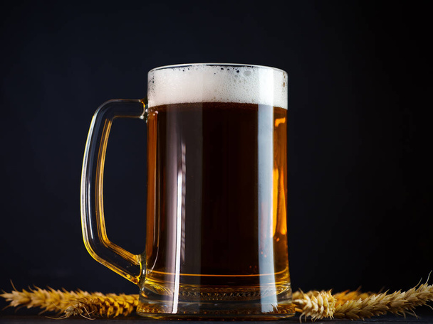 Une tasse de bière en verre sur une table sombre - Photo, image