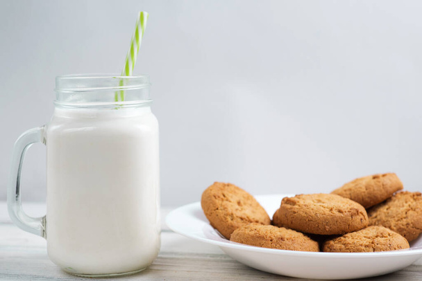 Melk en koekjes op een houten witte tafel - Foto, afbeelding