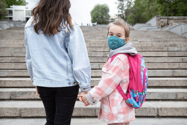 Zurück zur Schule. Coronavirus-Pandemiekinder gehen maskiert in die Schule. Freundschaftliche Beziehungen zu meiner Mutter. - Foto, Bild