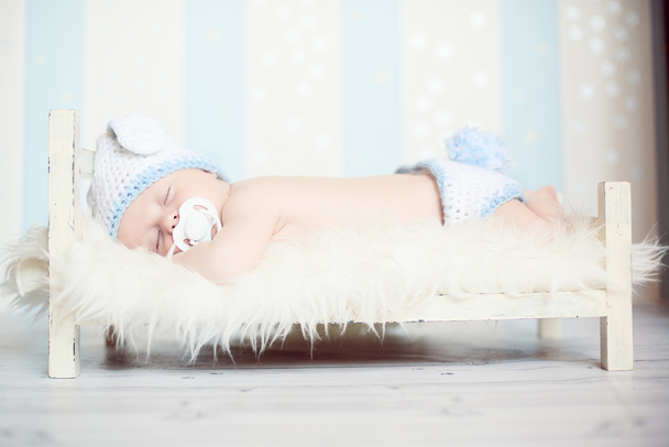 Baby liegt mit Schnuller im Mund auf einem Holzbett - Foto, Bild