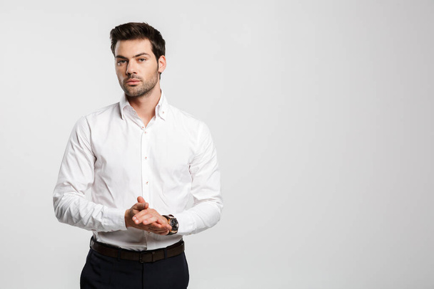 Image of young caucasian businessman in wristwatch posing and looking aside isolated over white background - Foto, afbeelding