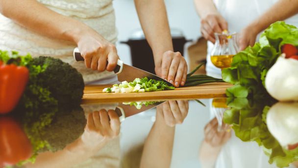 lähikuva ihmisen kädet ruoanlaitto keittiössä. Äiti ja tytär tai kaksi naispuolista ystävää leikkaa vihanneksia tuoretta salaattia varten. Ystävyys, perheillallinen ja elämäntapakonseptit - Valokuva, kuva