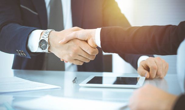 Business people shaking hands finishing up meeting or negotiation in sunny office. Business handshake and partnership concepts - Foto, Imagen