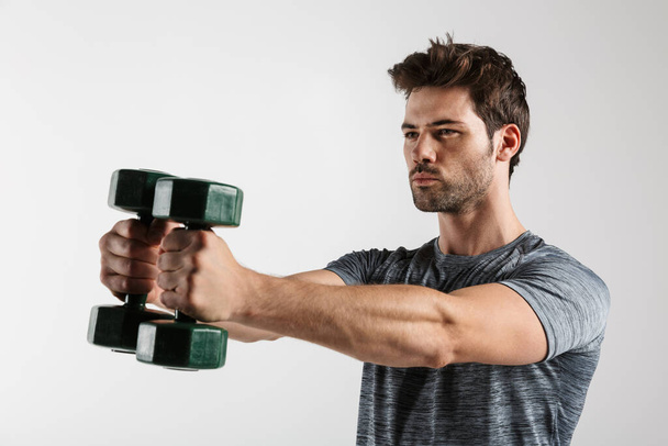 Image of handsome athletic man doing exercise with dumbbells while working out isolated over white background - Foto, afbeelding