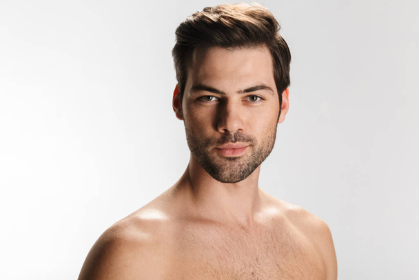 Photo of young half-naked man posing and looking at camera isolated over white background - Foto, Imagem