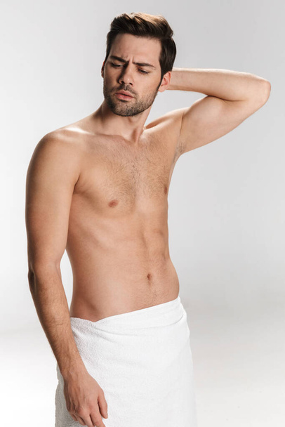 Photo of confused half-naked man posing in bath towel isolated over white background - Fotografie, Obrázek