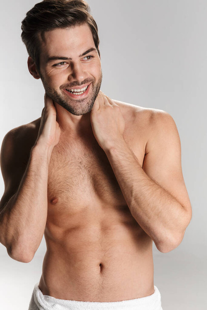 Photo of cheerful half-naked man in bath towel laughing and looking aside isolated over white background - Foto, Imagem