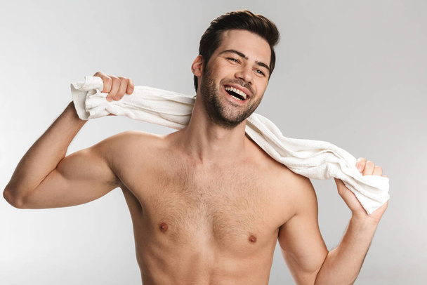 Photo of joyful half-naked man posing with towel and laughing isolated over white background - Foto, Imagem