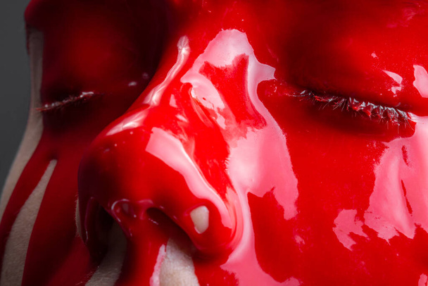 Shot of a girls face with spreading glossy red paint - Fotografie, Obrázek