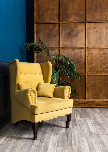 Stílusos sárga karosszék egy kék és fa falnak támasztva. Stílusos szék fal háttér, tenyér, divatos belső - Fotó, kép