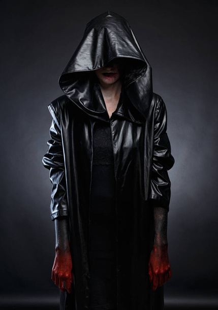 Foto de mujer en capucha de cuero negro con manos rojas
 - Foto, Imagen