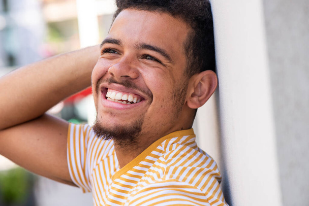 Close up side portrait of cheerful young mixed race man with hand behind head - Photo, Image