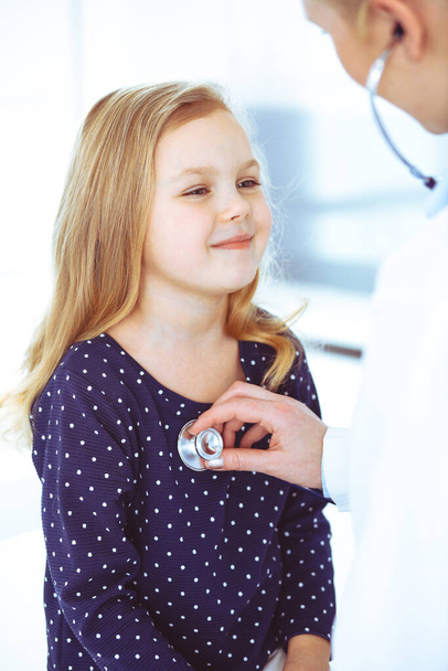 Doctor examining a child patient by stethoscope. Cute baby girl at physician appointment. Medicine concept. Toned photo - Fotografie, Obrázek