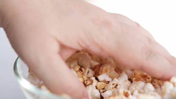 female hand selects delicious fried popcorn from a large glass bowl, the concept of sweets, anticipation of interesting, exciting events - Footage, Video