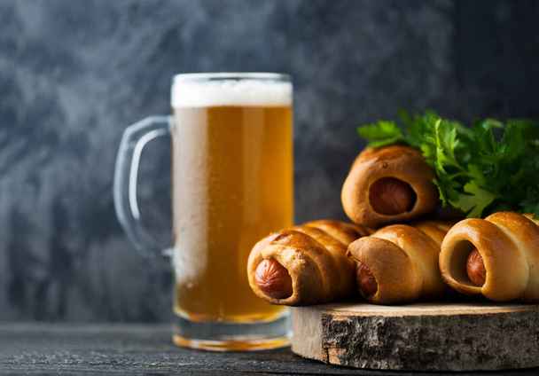 Wheat light beer in a mug glass and homemade sausages in a dough - Zdjęcie, obraz