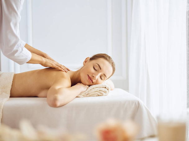 Beautiful woman enjoying back massage with closed eyes. Spa treatment concept - Φωτογραφία, εικόνα