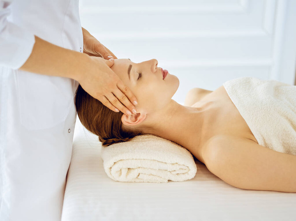 Beautiful woman enjoying facial massage with closed eyes. Spa treatment concept in medicine - Foto, afbeelding