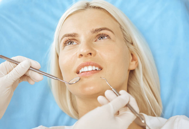 Smiling blonde woman examined by dentist at dental clinic. Healthy teeth and medicine concept - Photo, Image