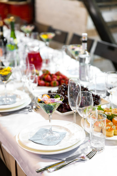 Mesa de banquete branca servida com pratos, copos e lanches no evento
 - Foto, Imagem