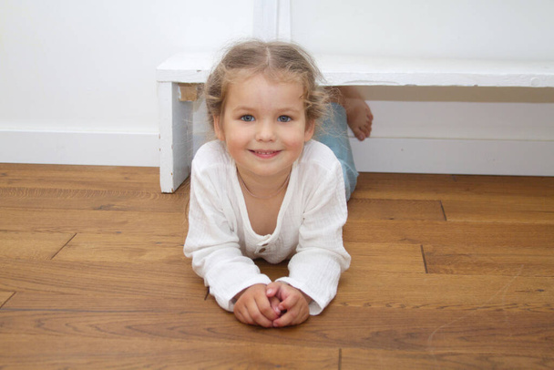 Μικρό χαριτωμένο κορίτσι σε ένα φωτεινό δωμάτιο, ένα ελάχιστο των αντικειμένων στο δωμάτιο - Φωτογραφία, εικόνα